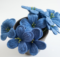 Handcrafted blue plumeria crochet flowers in a black ceramic pot on white background