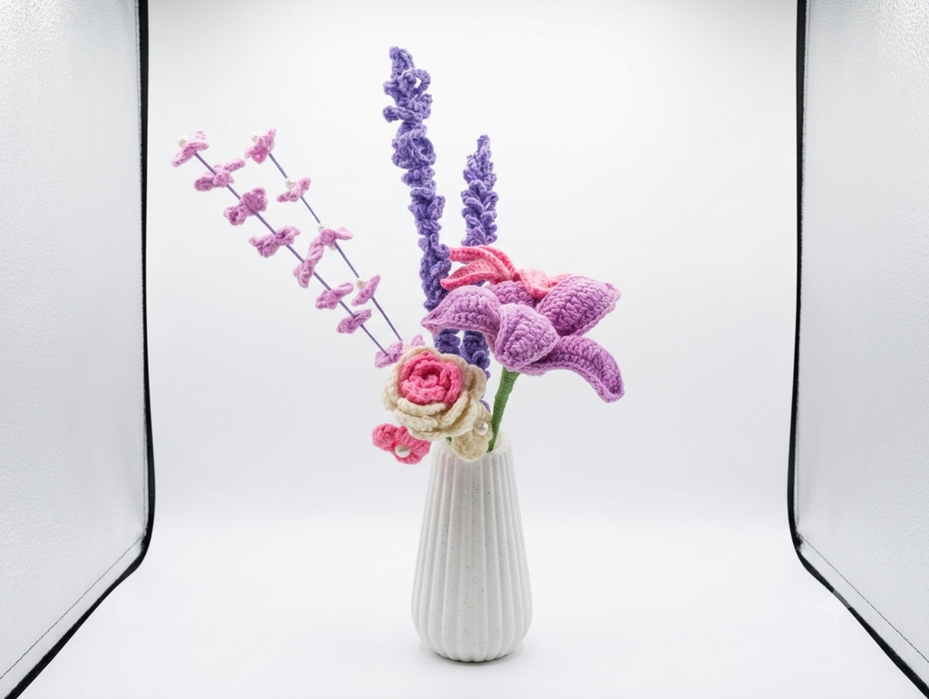 Handcrafted crochet bouquet with pink and purple flowers in white ribbed vase, studio shot